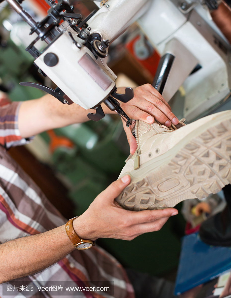 成熟的缝纫工在缝纫机上缝制皮靴